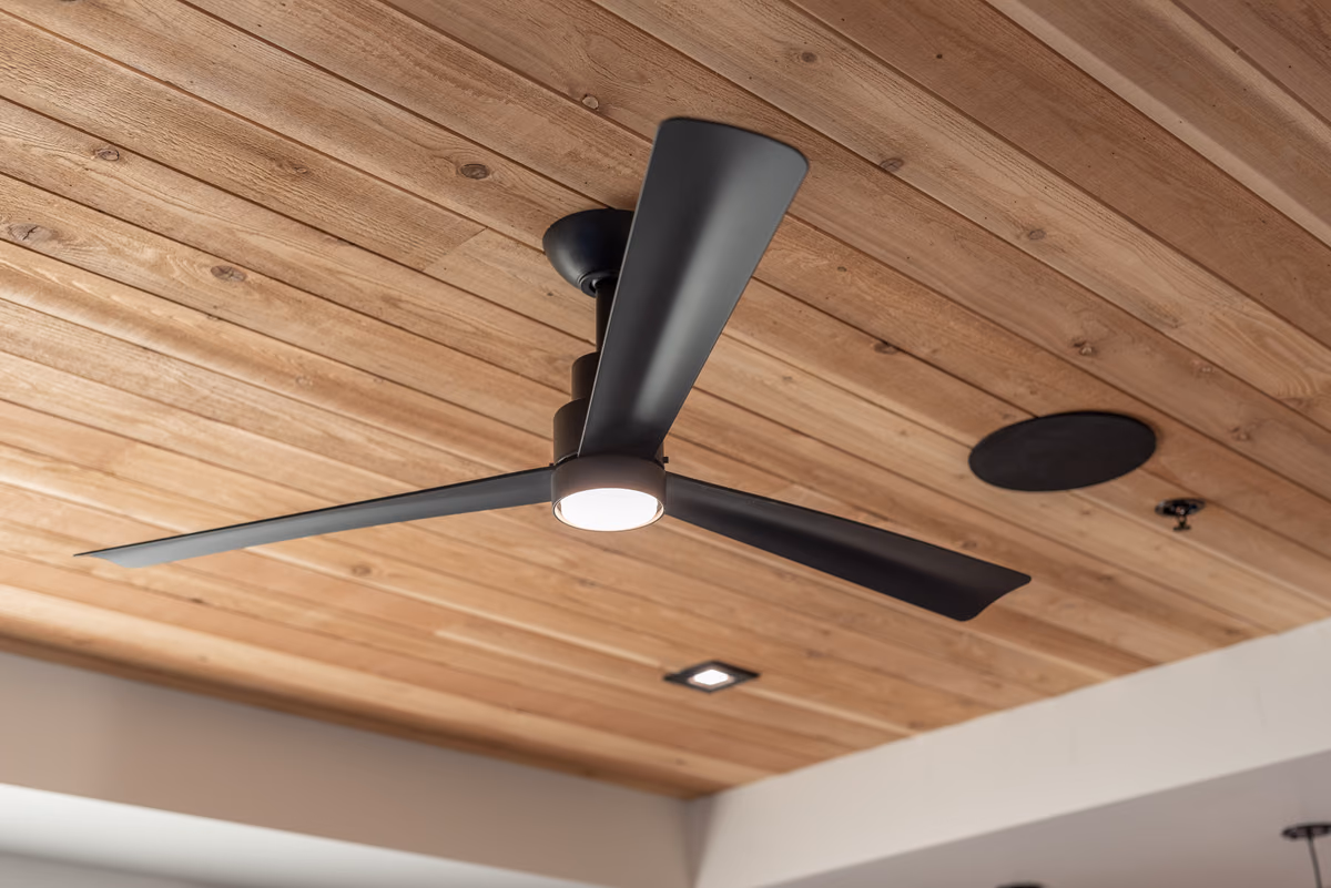 Cedar-plank ceiling with a black three-blade fan, a recessed square light, and a round black speaker.